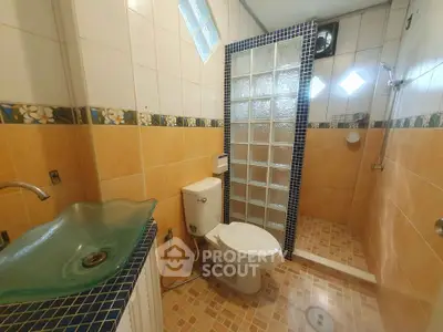 Charming bathroom with glass sink and tiled shower area in cozy home.