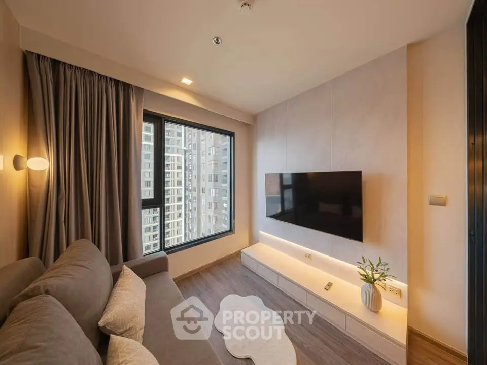 Modern living room with large window and wall-mounted TV in a stylish apartment.