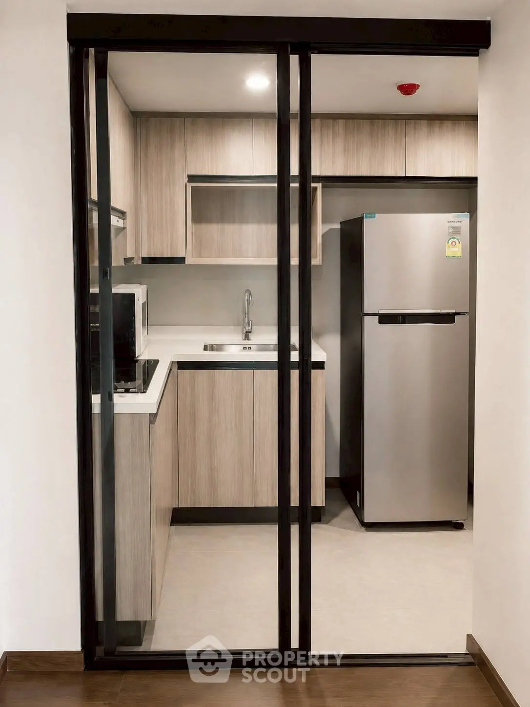 Modern kitchen with sleek cabinetry and stainless steel fridge in a compact layout.
