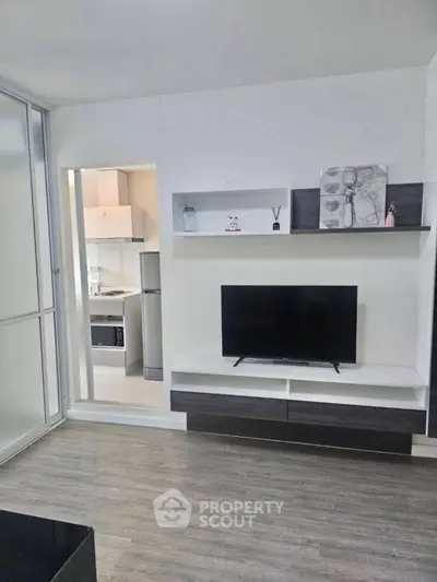 Modern living room with sleek TV stand and open kitchen view, perfect for contemporary living.