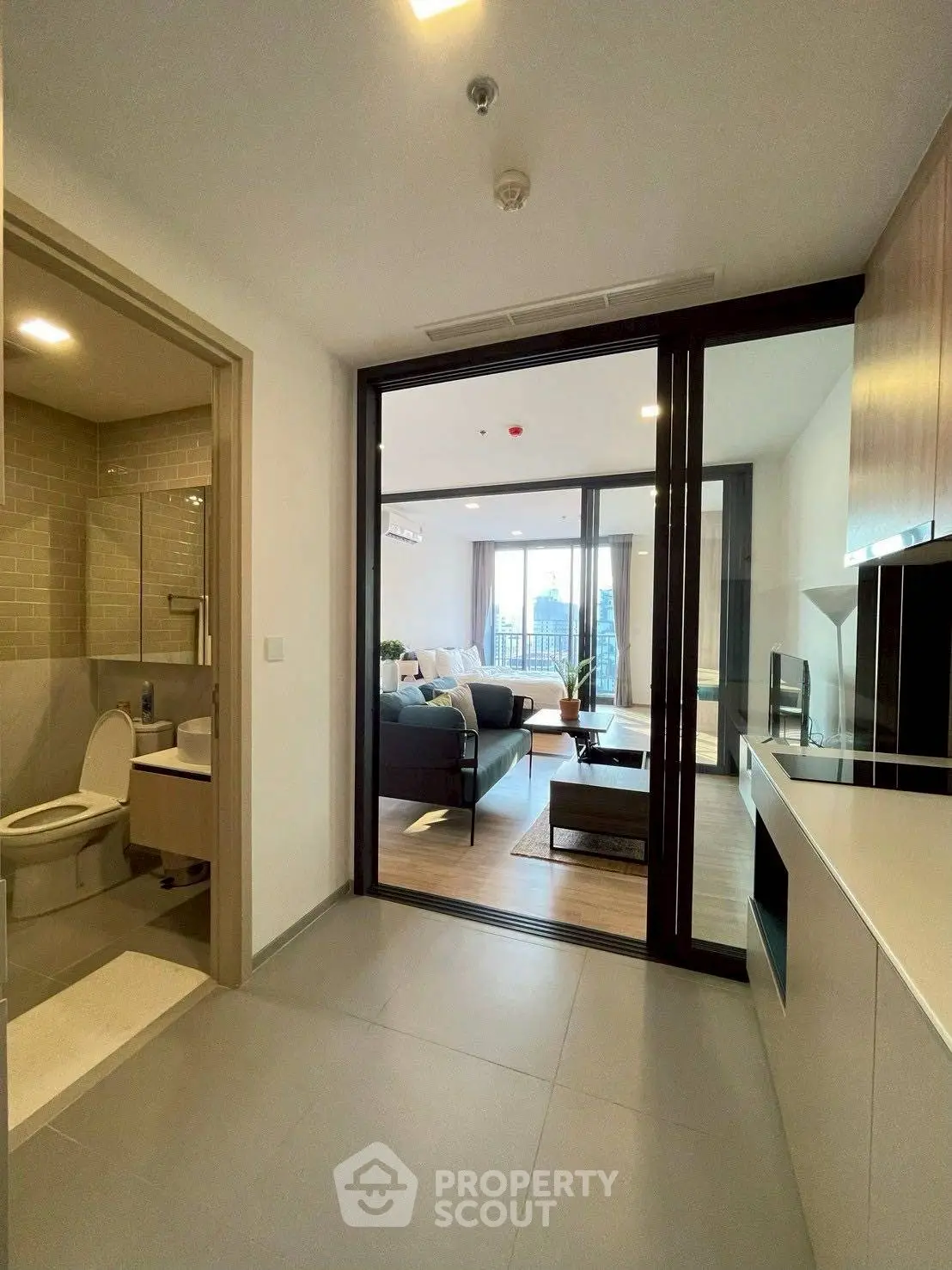 Modern apartment interior with open living room and adjacent bathroom, featuring sleek design and natural light.