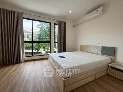 Spacious bedroom with large window and modern furnishings, perfect for natural light lovers.