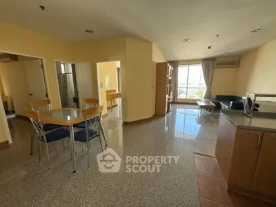 Spacious open-plan living room with dining area and large windows offering city views.