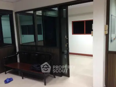 Spacious office interior with glass partitions and wooden bench, ideal for professional workspace.