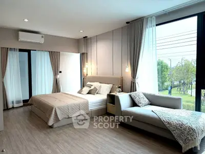 Luxurious bedroom with large windows and elegant decor, featuring a cozy bed and stylish chaise lounge.