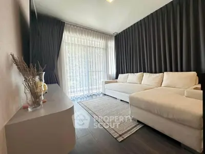 Modern living room with large windows and elegant curtains, featuring a cozy white sofa and stylish decor.