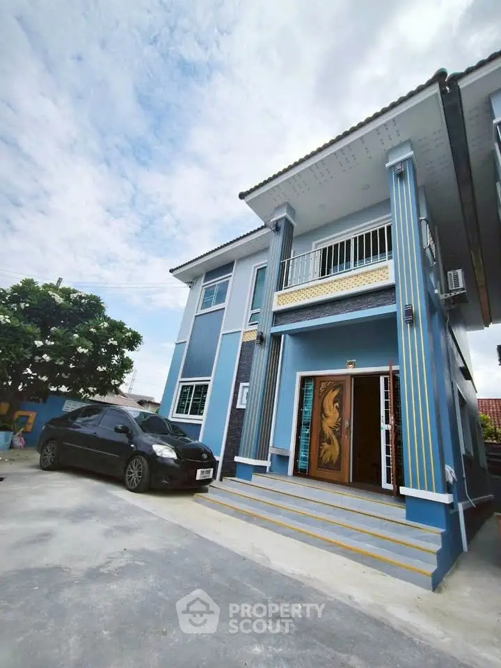 Stunning two-story blue house with elegant balcony and spacious driveway