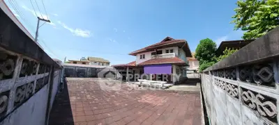 Charming two-story house with spacious courtyard and traditional architecture under clear blue sky.