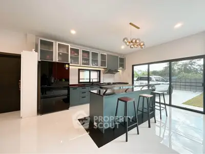 Modern kitchen with sleek island and large windows offering natural light and garden view.