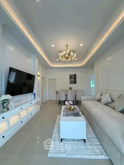 Elegant living room with modern decor, large TV, and stylish chandelier