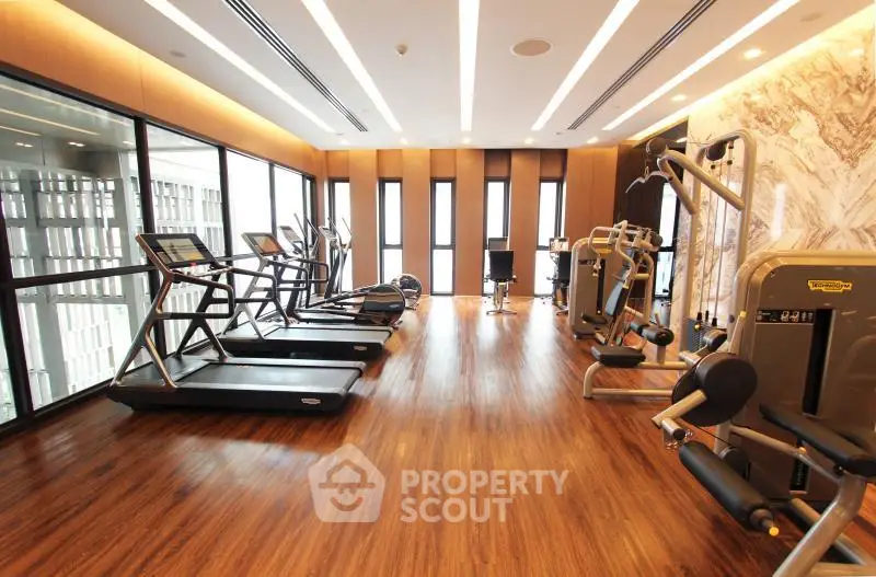 Luxurious modern gym with state-of-the-art equipment and wooden flooring in a high-end residential building.