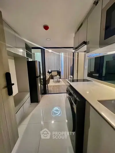 Modern kitchen with sleek appliances and open layout leading to stylish living area.