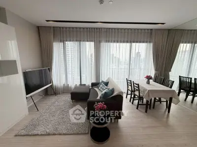 Spacious modern living room with large windows and city view, featuring elegant decor and dining area.