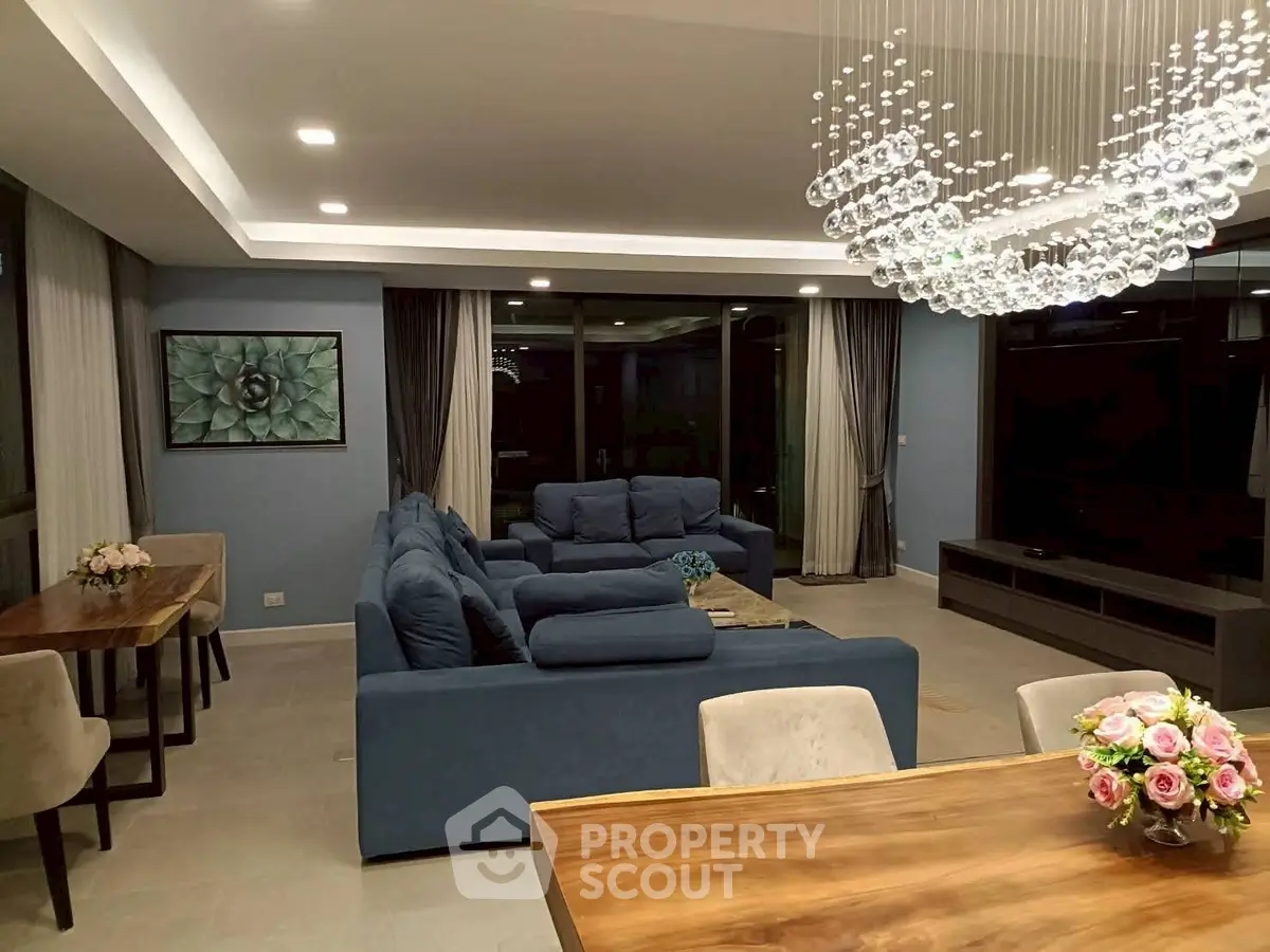 Luxurious modern living room with elegant chandelier and plush blue sofas