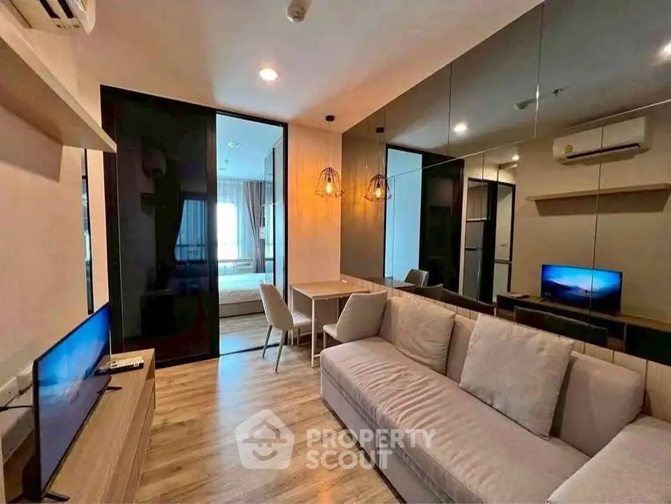 Modern living room with sleek design and mirrored wall, featuring cozy sofa and flat-screen TV.