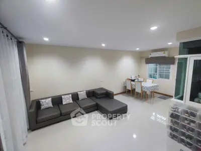 Spacious modern living room with sleek gray sectional sofa and dining area, perfect for entertaining.