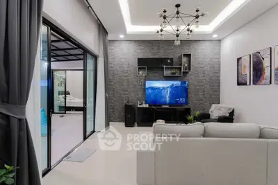 Modern living room with stylish decor and open layout leading to a balcony, featuring a chic chandelier and cozy seating.