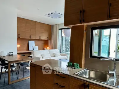Modern open-plan kitchen and living area with wooden cabinetry and large window view.