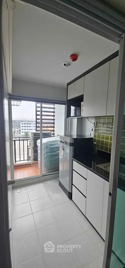 Modern kitchen with sleek cabinets and balcony view in urban apartment