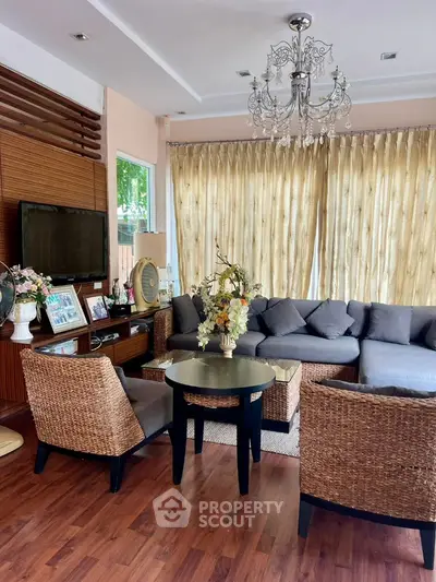 Elegant living room with chandelier, wicker furniture, and large windows.
