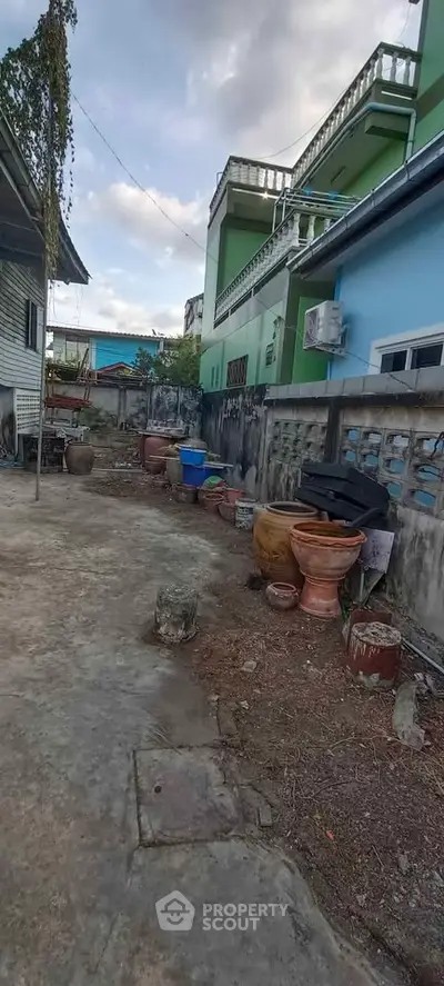 Spacious backyard with traditional pottery and green building exterior