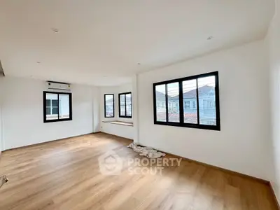 Spacious empty room with wooden flooring and large windows