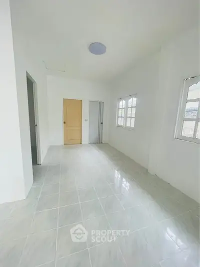 Spacious empty room with tiled flooring and natural light