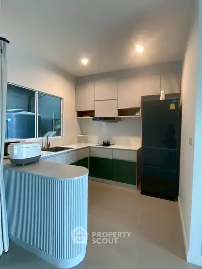 Modern kitchen with sleek cabinetry and black fridge in a stylish apartment.