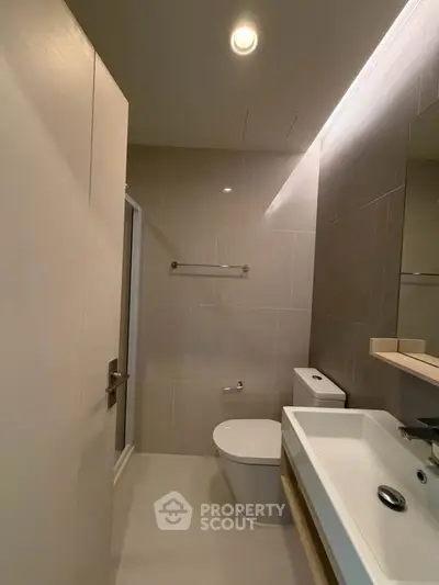 Modern bathroom with sleek fixtures and neutral tones, featuring a spacious shower and elegant sink.
