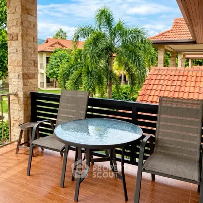Charming balcony with outdoor seating and lush garden view in tropical setting.