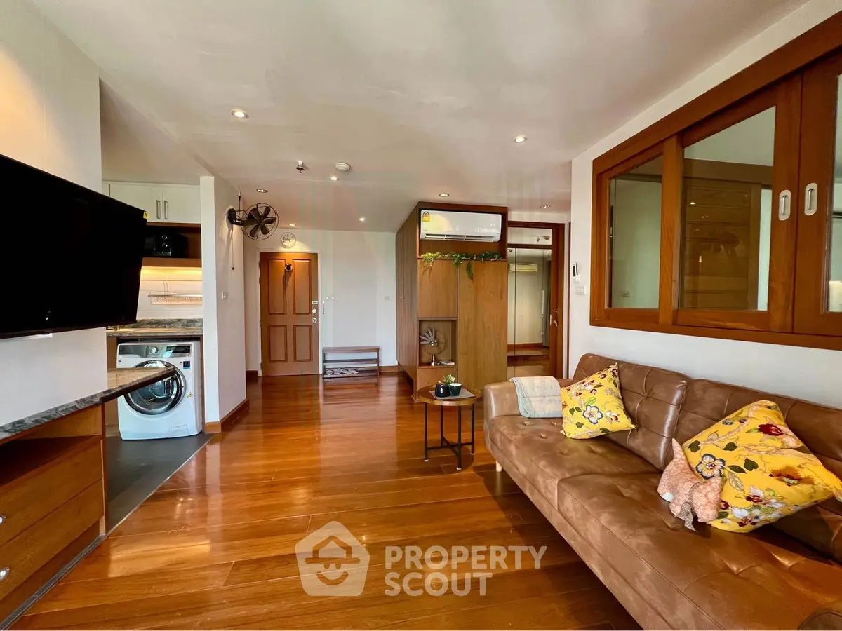 Charming living room with wooden floors, cozy sofa, and modern appliances in a stylish apartment.