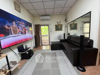 Cozy living room with large TV and modern black sofa, perfect for entertainment.