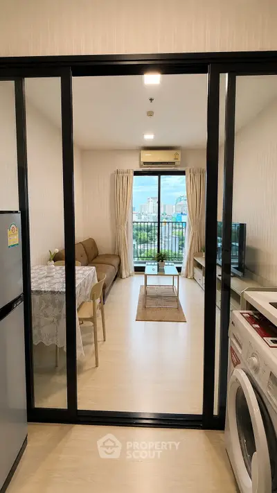 Modern living room with balcony view, featuring sleek furniture and in-unit washing machine.