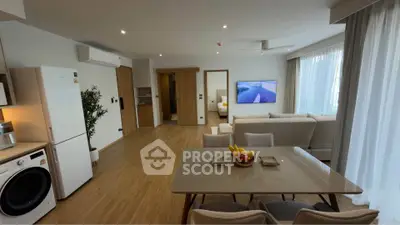 Modern open-plan living room with dining area, featuring sleek furniture and natural light.