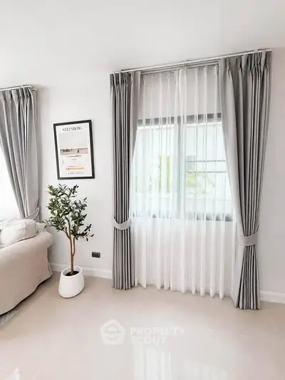 Elegant living room with modern decor and large window draped in stylish curtains.