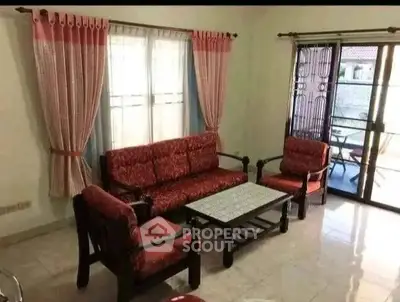 Charming living room with red upholstered furniture and natural light, perfect for cozy gatherings.