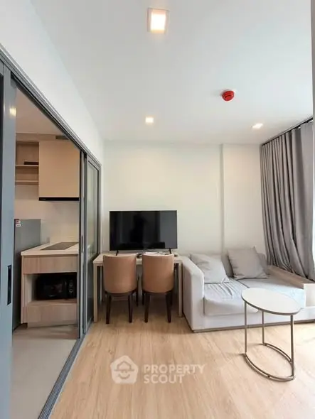 Modern living room with cozy sofa, dining area, and open kitchen in a stylish apartment.