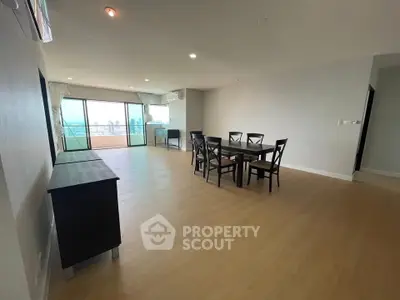 Spacious living room with dining area and large windows offering city views.