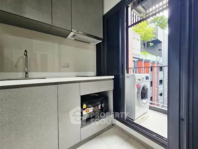 Modern kitchen with balcony and washing machine, sleek cabinetry and open layout.