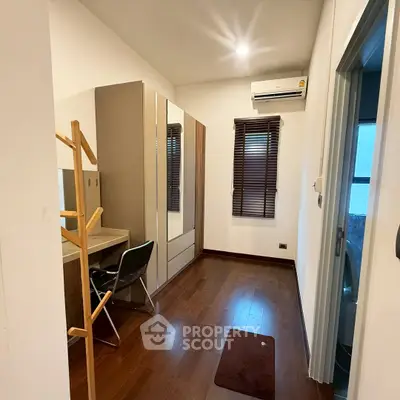 Modern study room with wooden flooring and air conditioning, featuring a desk and wardrobe.
