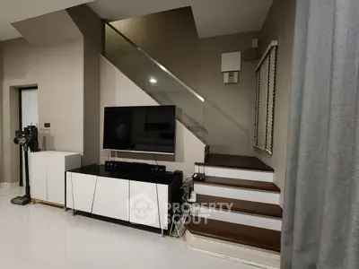 Modern living room with sleek staircase and entertainment center