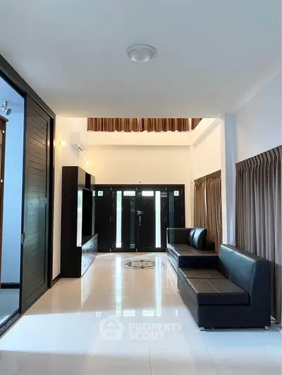 Spacious modern living room with sleek black sofas and large windows for natural light.