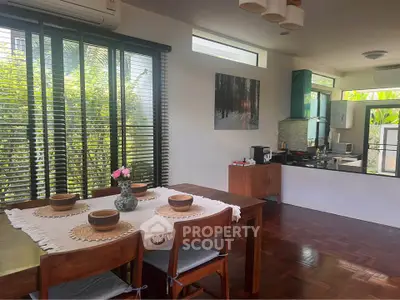 Charming dining area with natural light and garden view, featuring wooden furniture and modern kitchen setup.