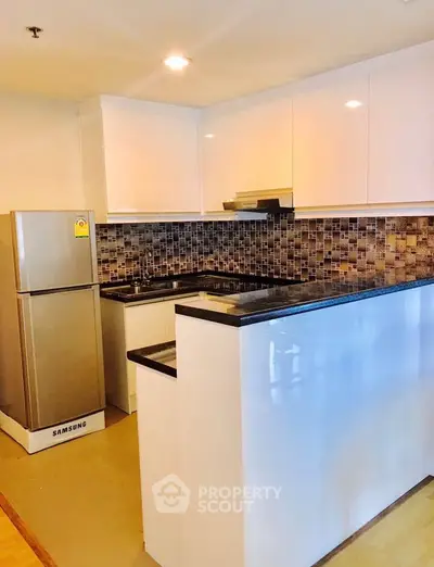Modern kitchen with sleek cabinetry and stylish backsplash in a contemporary apartment.