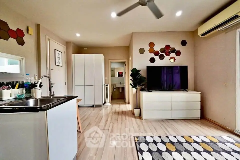 Modern living room with stylish decor and open kitchen layout, featuring a sleek TV setup and contemporary design.