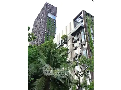 Modern architectural building with lush greenery and vertical gardens in urban setting.