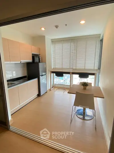 Modern kitchen with dining area and large window view in a stylish apartment.
