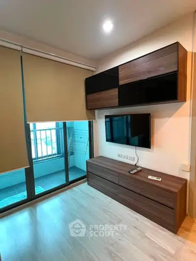 Modern living room with wall-mounted TV and balcony access in stylish apartment.