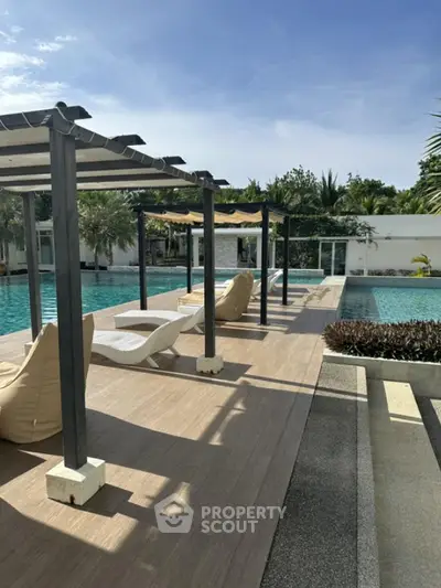 Luxurious poolside area with modern sun loungers and pergolas, perfect for relaxation and leisure.