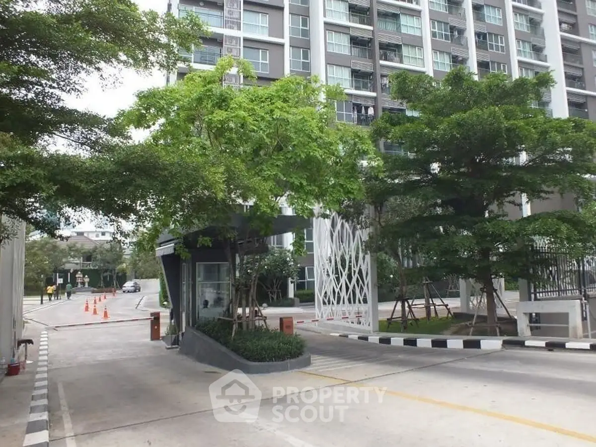 Modern residential building entrance with lush greenery and secure gated access.